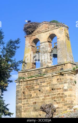 Pignon cloche de l'église San Martin del Obispo avec nid de cigogne et cloches sous le ciel bleu Banque D'Images
