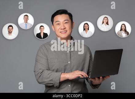 Recruteur avec ordinateur portable à la recherche d'un employé sur fond gris. Photos de candidats près de lui. Gestion des ressources humaines Banque D'Images