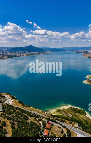 Vue aérienne sereine du lac Polyfytos en Grèce, entouré de collines luxuriantes et d'eaux bleues calmes. Un paysage naturel tranquille parfait pour les voyages et nat Banque D'Images