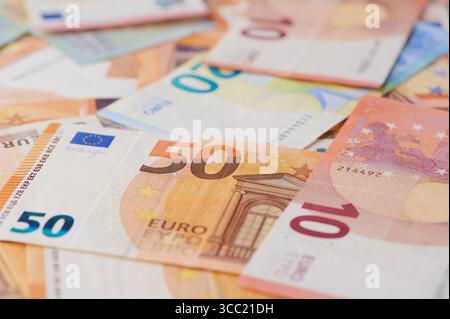 Billets en euros colorés de différentes coupures disposés de manière désordonnée sur Une surface. Banque D'Images