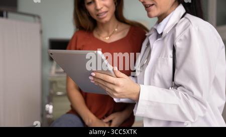 Mains du médecin féminin tenant le comprimé, en utilisant les dossiers électroniques Banque D'Images