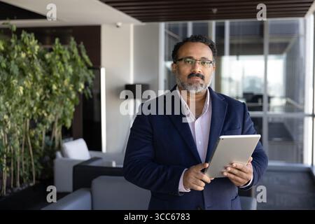 Homme d'affaires indien mature senior dans des lunettes élégantes tenant la tablette numérique Banque D'Images