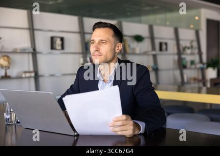 Homme professionnel hispanique réfléchi analysant le document financier légal Banque D'Images