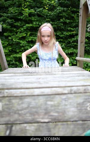 Fille grimpe sur le cadre d'escalade en bois Banque D'Images