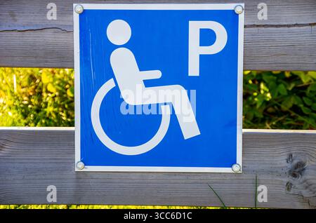 Panneau avec pictogramme pour l'espace de stationnement pour handicapés sur une clôture en bois, près de Henan sur Orust, Bohuslän, comté de Västra Götaland, Suède. Banque D'Images