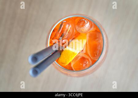 Cocktail Spritz Aperol avec pinces tenant un glaçon au-dessus du verre Banque D'Images