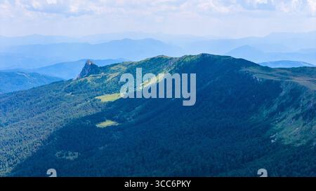 Chaîne de montagnes Jahorina couverte de forêt dense et de clairières ensoleillées, photographiée d'en haut Banque D'Images