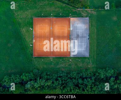 Vue de dessus des courts de tennis dans un cadre rural avec les arbres environnants et les lignes de terrain dégagées. Banque D'Images