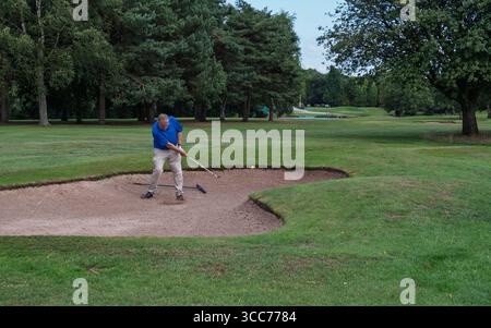 homme d'âge moyen en surpoids jouant au golf depuis le bunker Banque D'Images