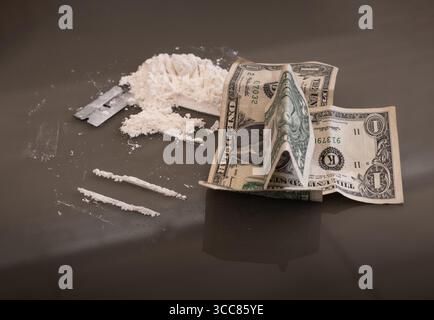 Scène simulée de cocaïne utilisant de la poudre de farine, une pile, une lame de rasoir et des billets de dollars américains sur une table sombre. Image conceptuelle illustrant de faux médicaments, financi Banque D'Images