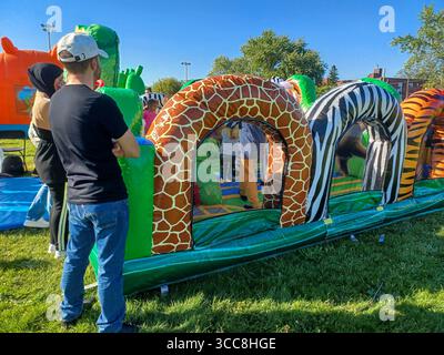Toronto, ON, Canada – 31 mai 2024 : les familles se rassemblent autour de grands toboggans gonflables et de parcours d’obstacles lors d’un événement pour enfants par un après-midi ensoleillé. Banque D'Images