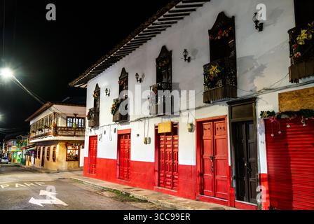 Bâtiments coloniaux colorés avec balcons traditionnels en bois décorés pour Noël sur un coin de rue la nuit à jardin, Colombie Banque D'Images