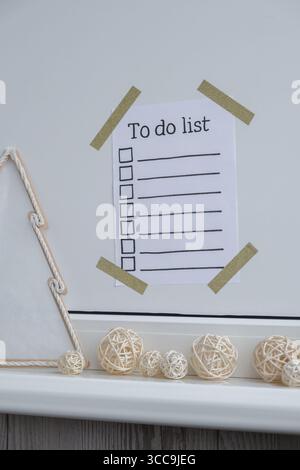 POUR FAIRE LA LISTE de contrôle texte sur papier note coller sur le mur avec un décor de Noël minimaliste à la main confortable. La nouvelle année vise des résolutions. Concept de planification festive et d'établissement d'objectifs discrets Banque D'Images