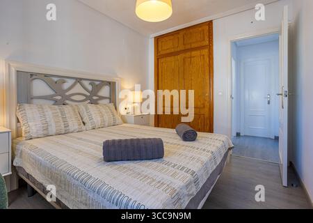Cette chambre double moderne dispose d''une armoire en bois, d''un éclairage tamisé et d''un décor neutre. Banque D'Images