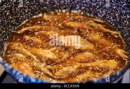 De petits poissons dorés grésillent dans de l'huile chaude, capturant une tradition rustique du sud de l'Italie. Croustillant dans une poêle mouchetée, cette scène reflète le patrimoine Banque D'Images
