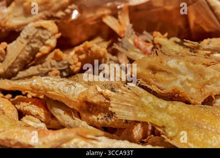 Petit poisson frit doré et croustillant avec nageoires et queues visibles, typique du sud de l'Italie. Leur texture croquante et leur aspect rustique évoquent une sensation traditionnelle Banque D'Images