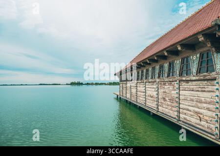 Hangar à bateaux traditionnel en bois avec des détails ornés sur le lac Palic, Serbie, s'étendant au-dessus de l'eau verte calme sous un ciel d'été lumineux. Mise au point sélective Banque D'Images