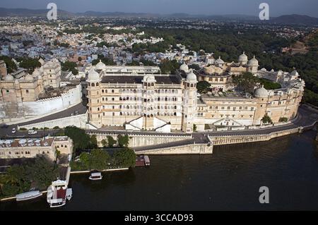 Vue aérienne du majestueux complexe City Palace, une symphonie d'architecture blanche reflétée dans les eaux tranquilles, contrastant avec la ville en toile de fond, Udaipur, Rajasthan, Inde. Banque D'Images