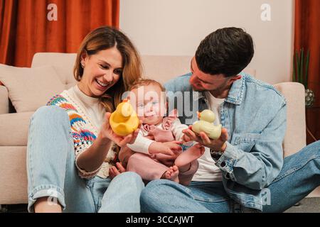 Une famille aimante profite de moments précieux ensemble, engagés dans des interactions ludiques avec de charmants canards en caoutchouc, créant une atmosphère joyeuse remplie de Banque D'Images