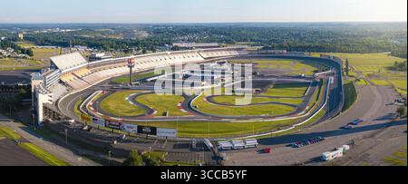 Concord, États-Unis - 28 juillet 2025 : vue aérienne du Charlotte Motor Speedway, où l'emblématique piste ovale brille sous le soleil, entourée de champs verdoyants et de forêts lointaines. Banque D'Images