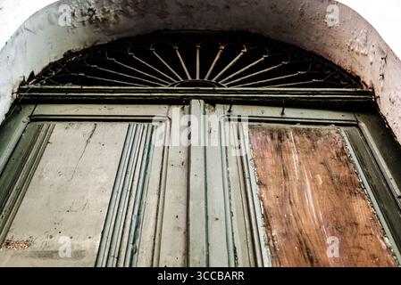 Une vieille porte en bois avec des barres de fer sur le dessus arqué. Vieux bâtiments. Banque D'Images