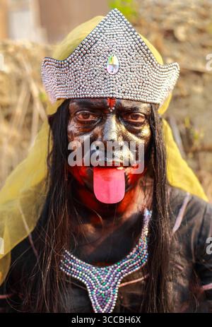 Chandanath hill, Bangladesh - 12 March 2021: View of a person adorned in dark makeup, a silver crown, and a striking necklace, tongue extended, embodying a cultural or theatrical persona. Banque D'Images