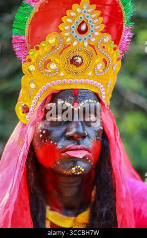 Chandanath hill, Bangladesh - 12 March 2021: View of a person adorned in vibrant Kali deity attire, with striking black face paint, red accents, and an elaborate golden headdress. Banque D'Images