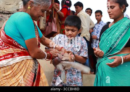 Chandanath hill, Bangladesh - 12 March 2021: View of a solemn ritual unfolding with contrasting emotions as an elderly woman prepares a goat for sacrifice. Banque D'Images