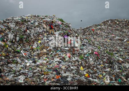 Chattogram, Bangladesh - 05 octobre 2020 : vue d'enfants naviguant dans le vaste paysage texturé d'une décharge sous un ciel lourd et couvert. Banque D'Images