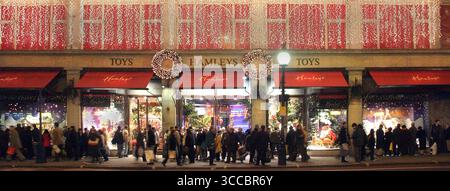 Hamleys Toys le célèbre magasin de shopping vu à l'extérieur 2004 Archival nuit vue nocturne de la boutique Regent Street dans une scène de lumières de Noël des années 2000 avec une élévation décorée au-dessus d'un trottoir piétonnier très fréquenté avec des acheteurs se rassemblant autour de grandes fenêtres affichant des marchandises pour enfants à vendre ciblant la saison d'achat de Noël présent à Regent Street West End Londres Angleterre Royaume-Uni Banque D'Images