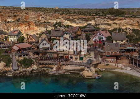 Vue sur Popeye Village à Anchor Bay, Malte, par une journée ensoleillée avec un ciel bleu vif, capturant le village coloré et le littoral. Banque D'Images