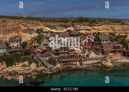 Vue sur Popeye Village à Anchor Bay, Malte, par une journée ensoleillée avec un ciel bleu vif, capturant le village coloré et le littoral. Banque D'Images