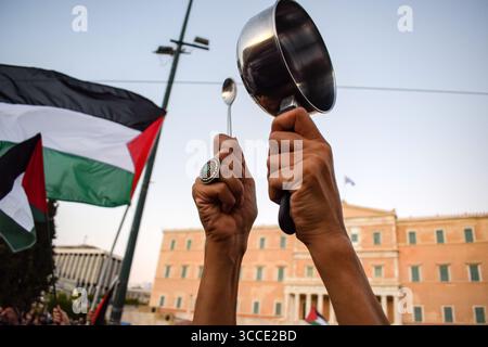 Athènes, Grèce, 10 août 2025. Un manifestant frappe un pot vide devant le Parlement lors d'une manifestation condamnant la famine à Gaza et l'arrivée de soldats israéliens en vacances en Grèce. Le rallye était l'un des 100 événements similaires organisés à travers la Grèce le même jour. Crédit : Dimitris Aspiotis/Alamy Live News Banque D'Images