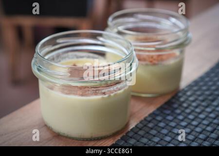 Paire de pots à dessert crémeux sertis sur un tapis, garnis et préparés pour le service. Banque D'Images