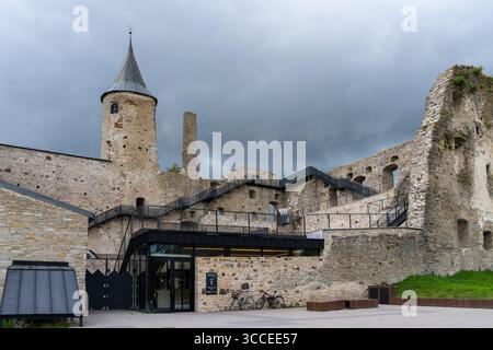 10 août 2025, Haapsalu, Estonie – ruines du château de Haapsalu avec tour et entrée moderne des visiteurs sous le ciel spectaculaire. Banque D'Images