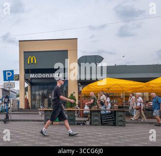 Kiev, Ukraine - 25 juillet 2025 : les gens apprécient la journée d'été près du restaurant McDonald's avec des parasols jaunes à Kiev, Ukraine, avec un jeune homme Banque D'Images