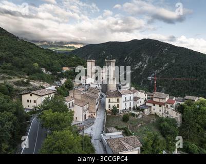 Vue aérienne des tours anciennes s'élèvent du cœur d'un village pittoresque niché au milieu de collines verdoyantes, baigné dans la douce lueur du soleil couchant, parc national de Majella, province de L'Aquila, Italie. Banque D'Images