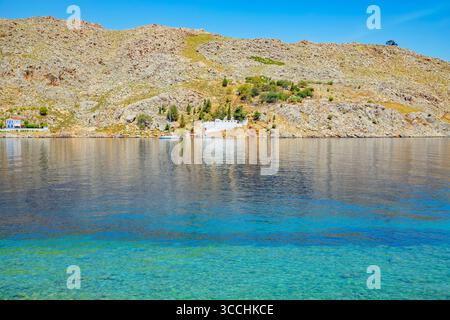 Vue sur l'océan et le monastère au loin de la plage de Nimborio, Nimborio, Symi Island, Dodécanèse Islands, Grèce Banque D'Images