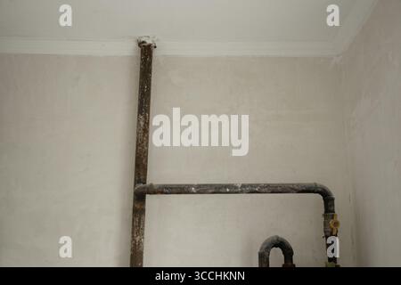 Tuyau en métal de gaz avec valve sur le mur blanc dans l'appartement lors de la rénovation close-up Banque D'Images
