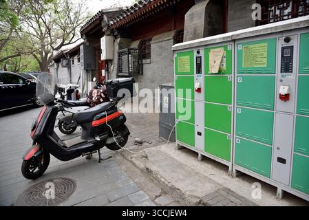 Recharge de scooter électrique à une station de recharge publique dans la vieille rue traditionnelle hutong dans le centre de Pékin, Chine le 19 avril 2024 Banque D'Images