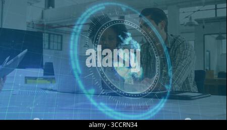 Discuter avec les collègues examinant les données du projet sur ordinateur portable dans un bureau ouvert, avec globe holographique Banque D'Images