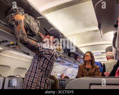 6 février 2020 : un passager d'une compagnie aérienne tatoué transporte des bagages dans un bac supérieur tandis que d'autres passagers attendent en ligne pour être assis à l'aéroport John F. Kennedy de New York. (Crédit image : © Spencer Grant/ZUMA Press Wire) Banque D'Images