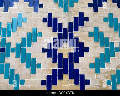 Motif géométrique de carreaux islamiques dans des tons bleu profond et turquoise sur un mur traditionnel de briques beiges, photographié au Registan à Samarcande, Ouzbékistan Banque D'Images
