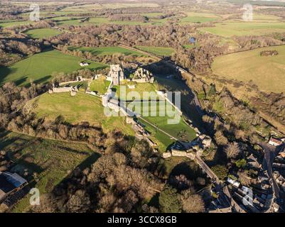 Vue aérienne d'une ancienne ruine de château se trouve au sommet d'une colline herbeuse, entourée de champs verdoyants et de forêts denses, projetant de longues ombres, Trim, Irlande. Banque D'Images