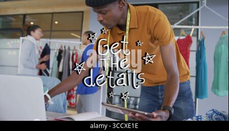 Penchant concepteur de mode masculin ajustant la tablette et l'ordinateur portable dans la salle d'exposition de mode, avec des supports de vêtements Banque D'Images