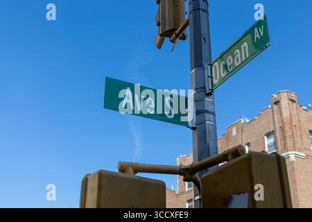 Un coin de rue avec un ciel bleu clair au-dessus. Deux panneaux de rue verts sont bien en vue sur un poteau de service, indiquant Banque D'Images