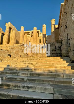 Coucher de soleil heure d'or à l'entrée du complexe de l'Acropole (Acrópole Propileia) à Athènes, Grèce, avec des touristes marchant dans les escaliers. Banque D'Images