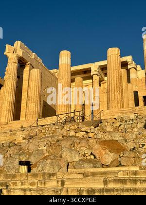 Coucher de soleil heure d'or à l'entrée du complexe de l'Acropole (Acrópole Propileia) à Athènes, Grèce, avec des touristes marchant dans les escaliers. Banque D'Images