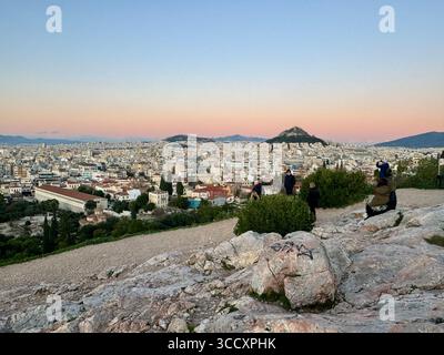 Couleurs de coucher de soleil peignant le ciel au-dessus d'Athènes, vu de la colline d'Aréopage avec l'Acropole et la colline de Lycabette en arrière-plan. Banque D'Images