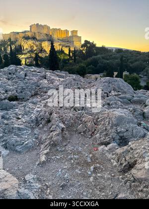 Lever de soleil sur la colline d'Areopagus avec la lumière chaude du matin illuminant l'Acropole et le paysage urbain d'Athènes. Banque D'Images